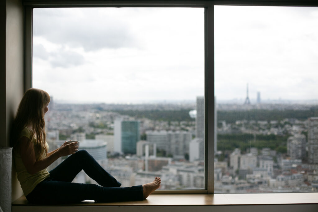 Alena Gomes Rodrigues sitting by a window, Eiffel Tower background